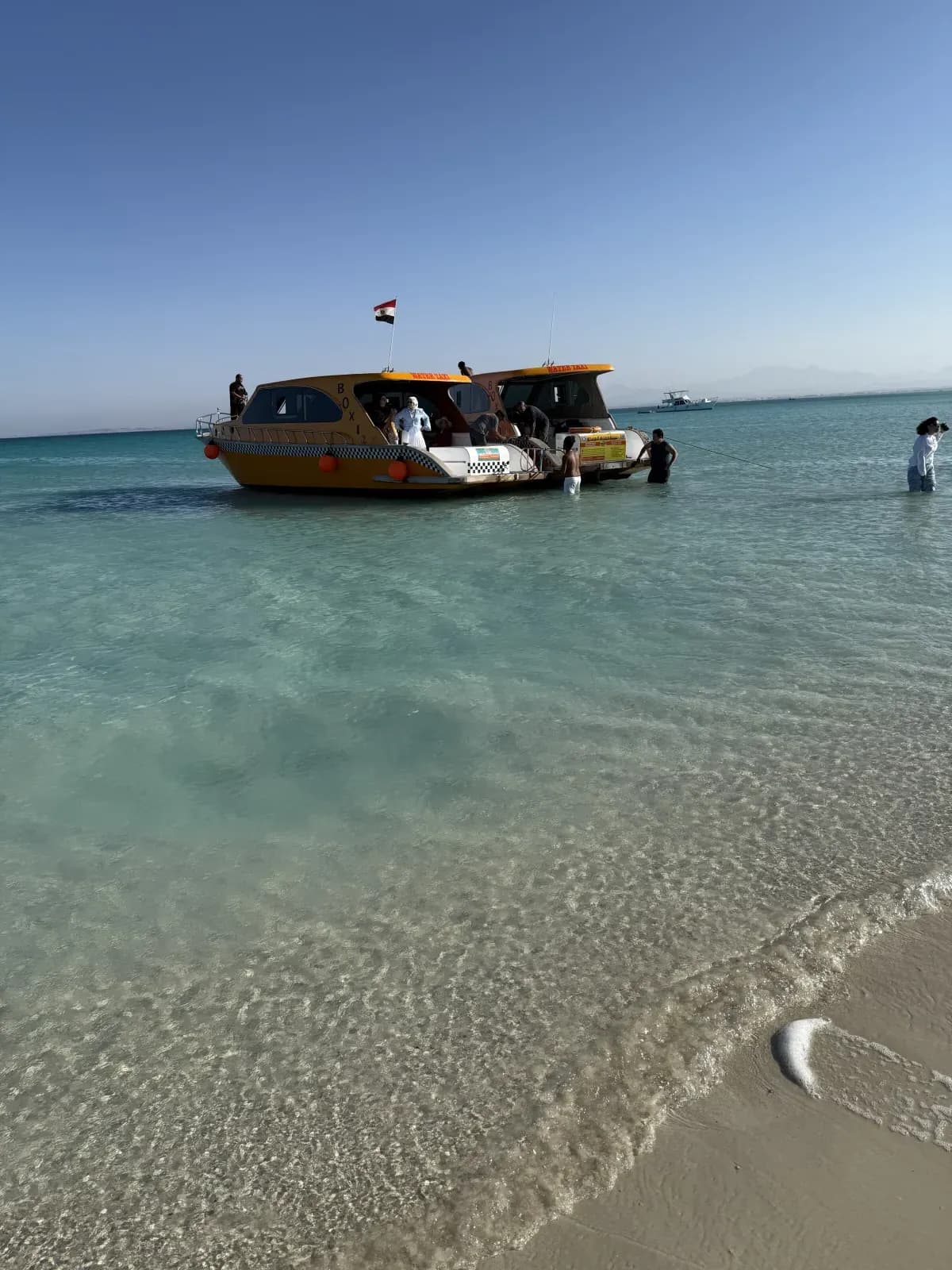 Deux bateaux-taxis Boxi dans l'eau turquoise, au bord de la plage d'une île près de Hurghada