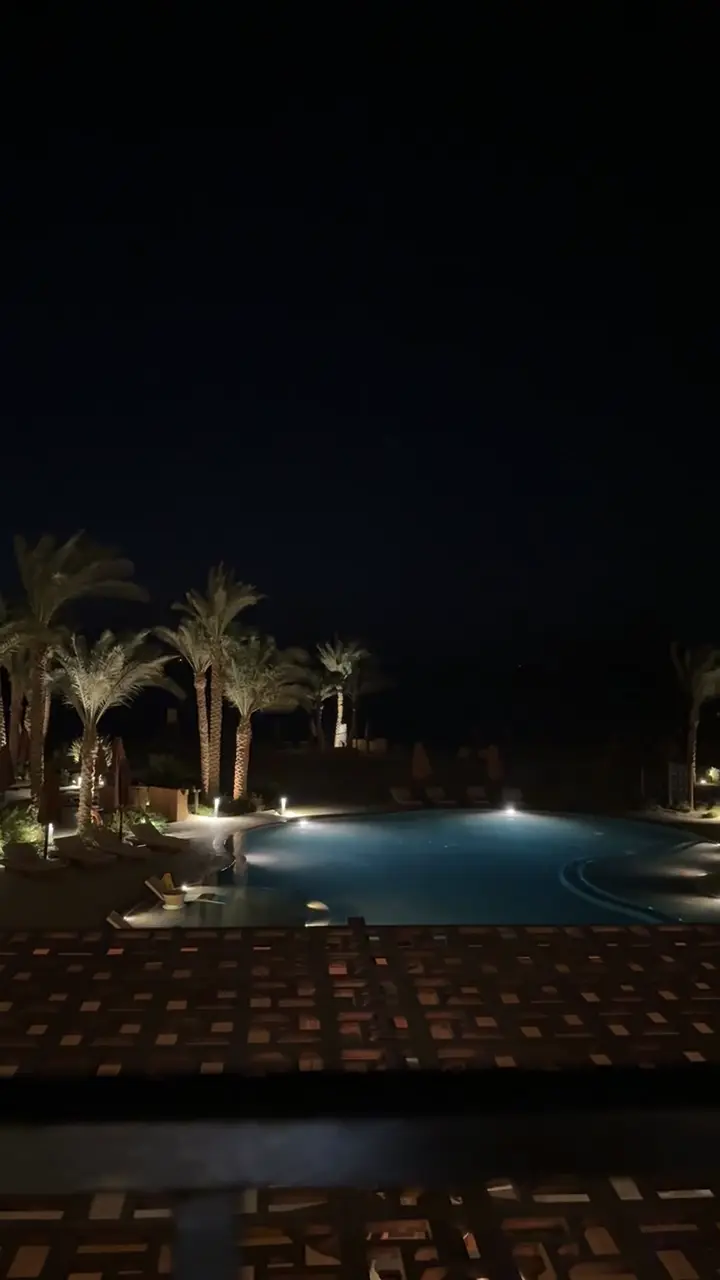 Piscine éclairée la nuit entre les palmiers, à El Gouna