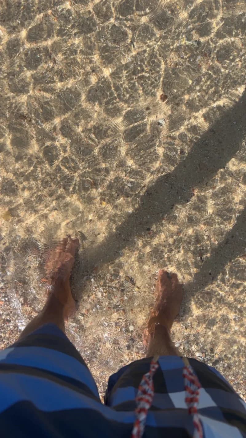 Füße in glasklarem Wasser über Sand im Roten Meer