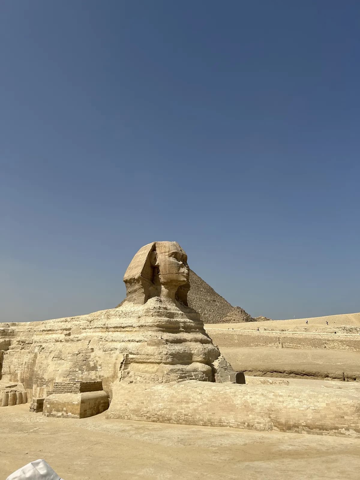 Le Sphinx de Gizeh devant une pyramide, sous le ciel bleu du Caire