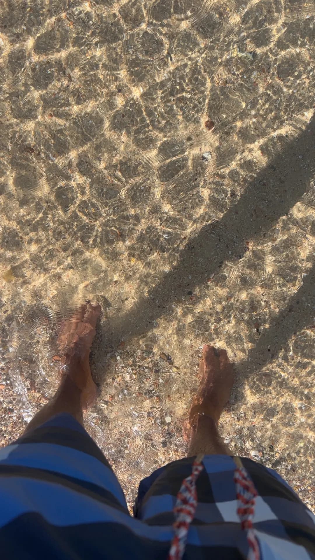 Pieds dans une eau cristalline au-dessus du sable, en mer Rouge